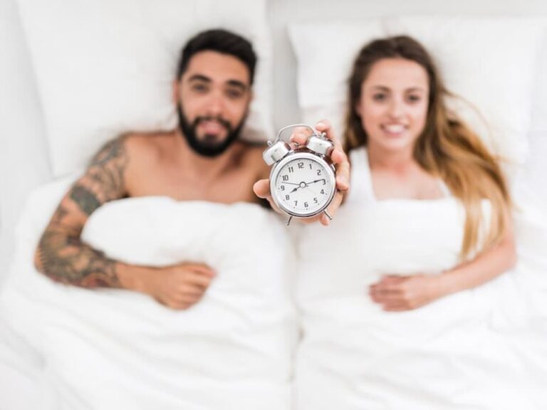 Pareja mostrando reloj en la cama