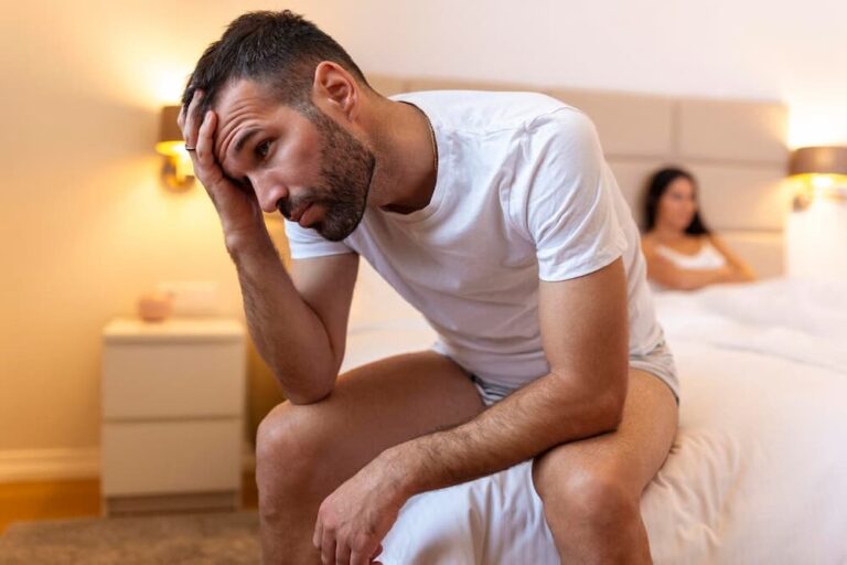 Hombre frustrado en la cama y mujer de fondo