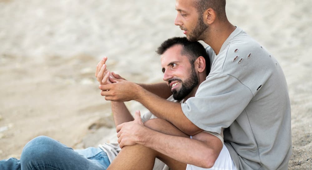 Pareja gay sobre la arena